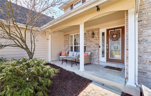 entrance to property featuring outdoor lounge area, brick siding, and a porch