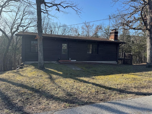 view of front of home with faux log siding, a front lawn, and a chimney