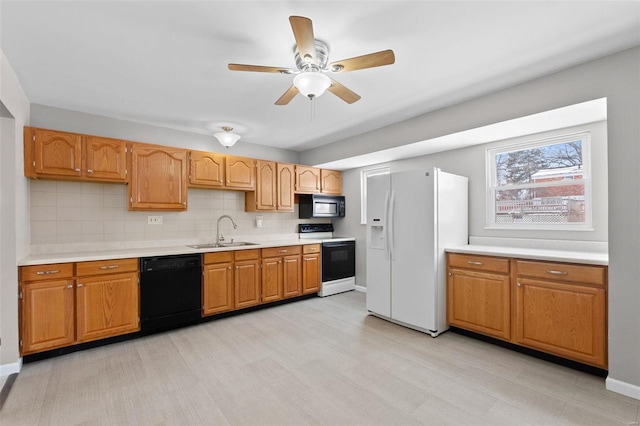 kitchen featuring a sink, light countertops, baseboards, tasteful backsplash, and black appliances