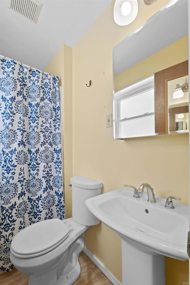 bathroom with toilet, visible vents, and a sink