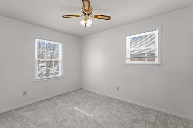 spare room with light carpet, plenty of natural light, visible vents, and ceiling fan