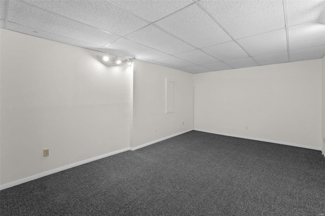 below grade area with baseboards, dark colored carpet, and a drop ceiling