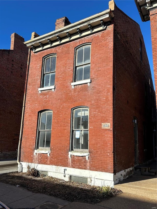 view of side of home with a chimney and brick siding