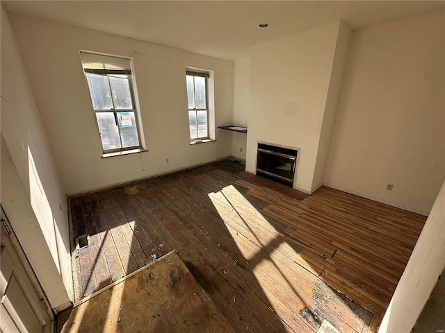 unfurnished living room featuring dark wood-type flooring and a glass covered fireplace