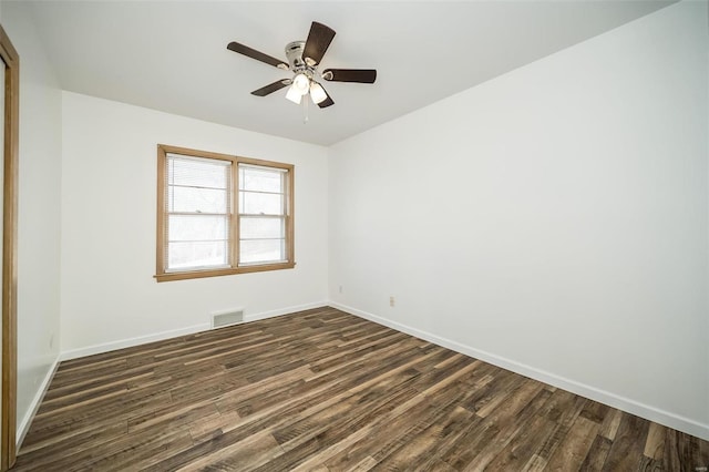 spare room with dark wood-type flooring, visible vents, baseboards, and a ceiling fan