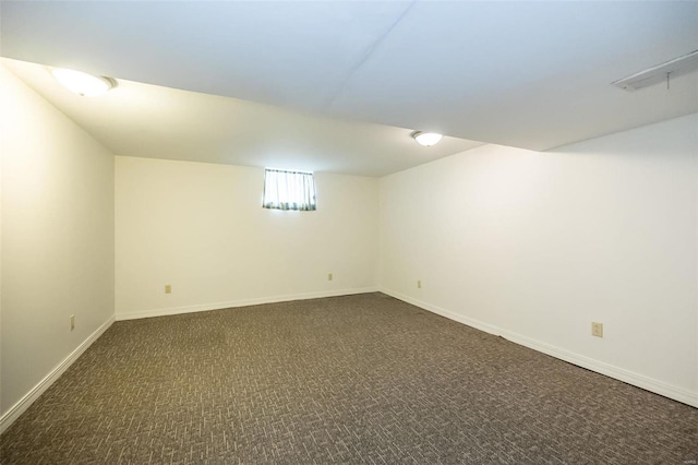 basement with dark carpet and baseboards