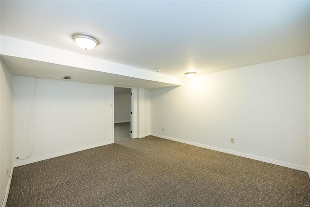 finished below grade area featuring dark colored carpet, visible vents, and baseboards