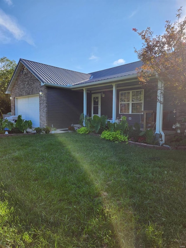 single story home with metal roof, a porch, a garage, brick siding, and a front yard