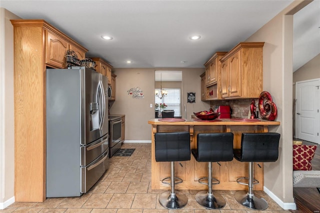 kitchen with stainless steel appliances, decorative backsplash, a chandelier, a kitchen bar, and kitchen peninsula