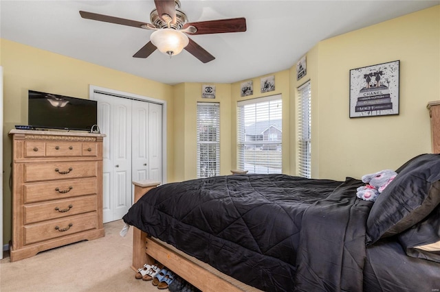 bedroom with ceiling fan, a closet, and light colored carpet