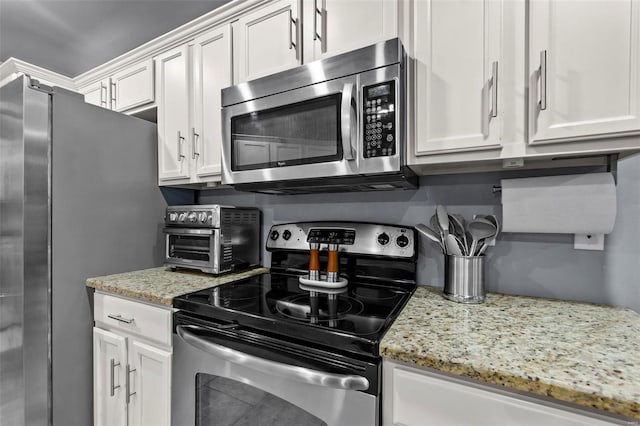 kitchen with appliances with stainless steel finishes, white cabinets, and light stone counters