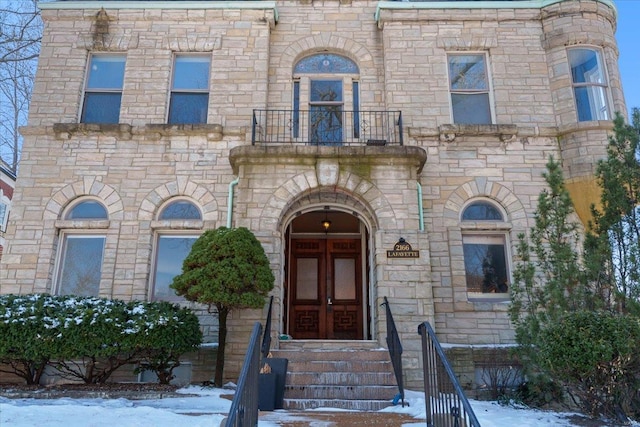 view of front of property with entry steps, french doors, and a balcony