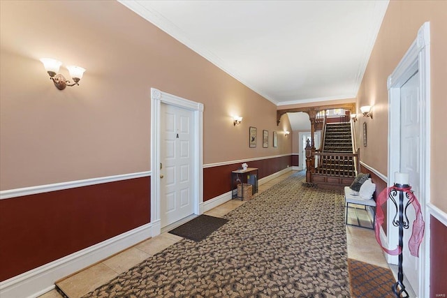 hallway featuring ornamental molding, wainscoting, stairway, and light tile patterned floors