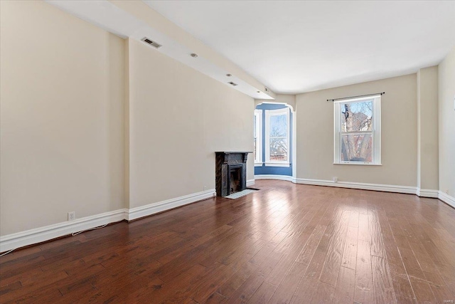 unfurnished living room featuring a fireplace with flush hearth, visible vents, baseboards, and wood finished floors