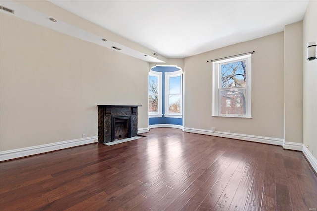 unfurnished living room featuring dark wood-style floors, a fireplace with flush hearth, visible vents, and baseboards