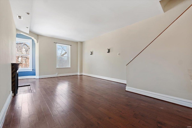 unfurnished living room with dark wood-type flooring, visible vents, and baseboards