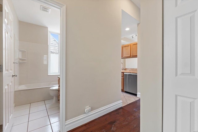 corridor with visible vents, baseboards, and light tile patterned flooring