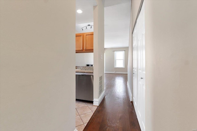 corridor with light wood finished floors, visible vents, and baseboards