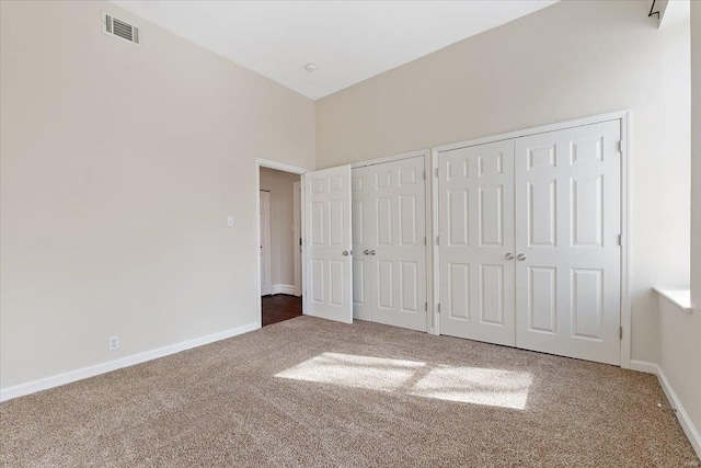 unfurnished bedroom featuring baseboards, carpet, visible vents, and multiple closets