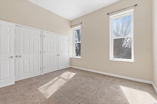 unfurnished bedroom with carpet floors, baseboards, and multiple closets