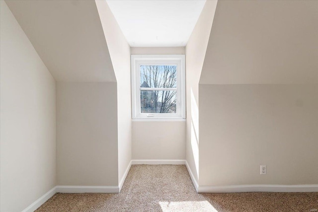 additional living space with lofted ceiling, light colored carpet, and baseboards