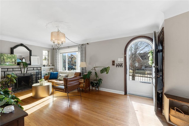 foyer featuring a chandelier, baseboards, a stone fireplace, and wood finished floors