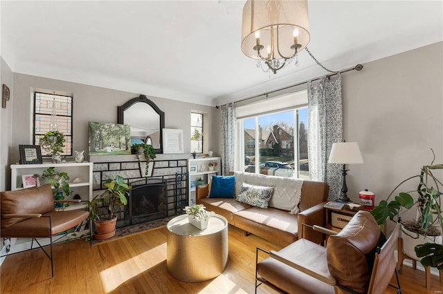 living area with a fireplace, an inviting chandelier, and wood finished floors