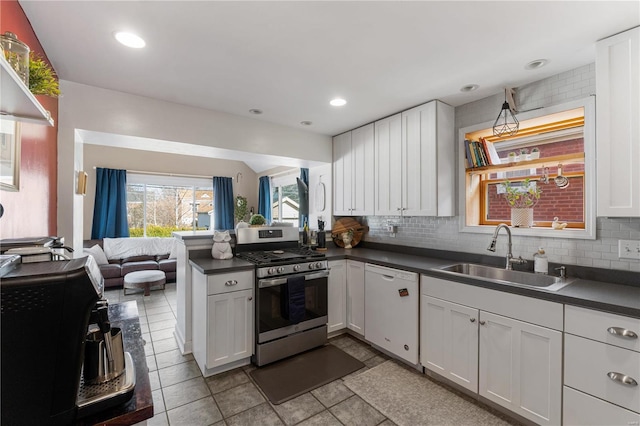 kitchen with dark countertops, a sink, stainless steel range with gas cooktop, and white dishwasher