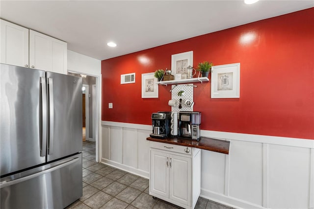 kitchen with visible vents, a wainscoted wall, freestanding refrigerator, recessed lighting, and white cabinets