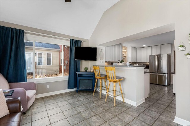 kitchen featuring open shelves, a peninsula, freestanding refrigerator, white cabinets, and a kitchen bar