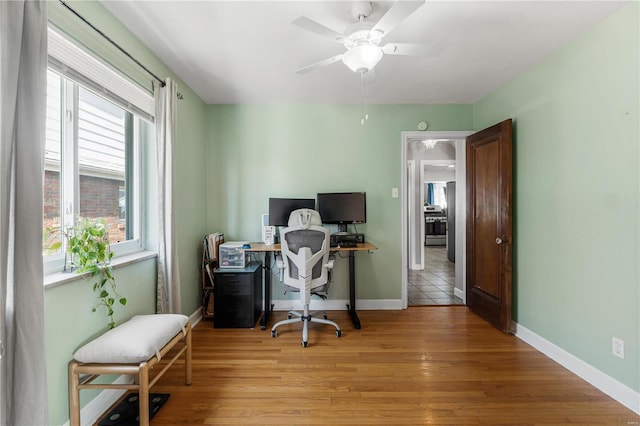 office featuring a ceiling fan, light wood-type flooring, and baseboards