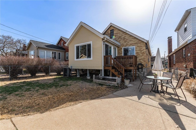 view of front of home with a patio, brick siding, and fence