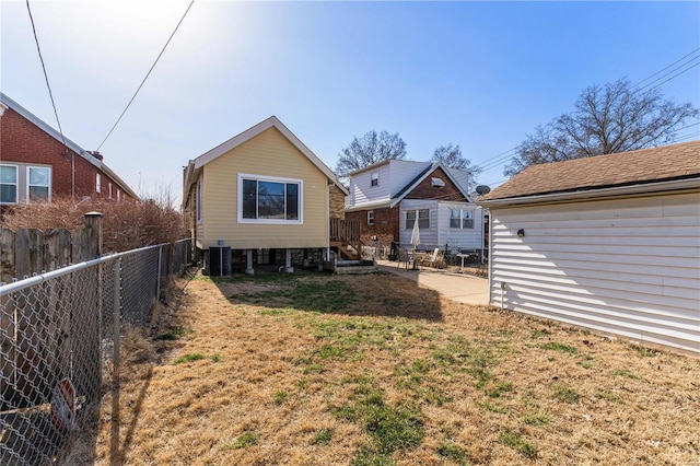 rear view of house with a yard, central air condition unit, and a fenced backyard