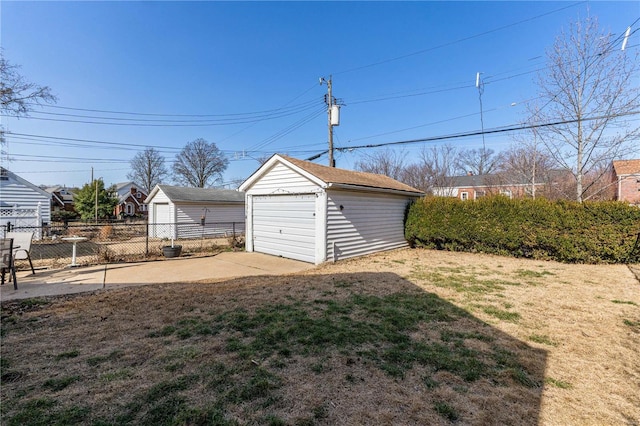 view of yard featuring a detached garage, an outdoor structure, and fence