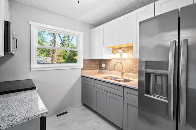 kitchen featuring white cabinetry, sink, stainless steel appliances, and light stone countertops