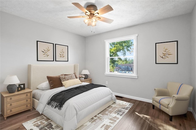 bedroom with dark wood-type flooring, ceiling fan, and a textured ceiling