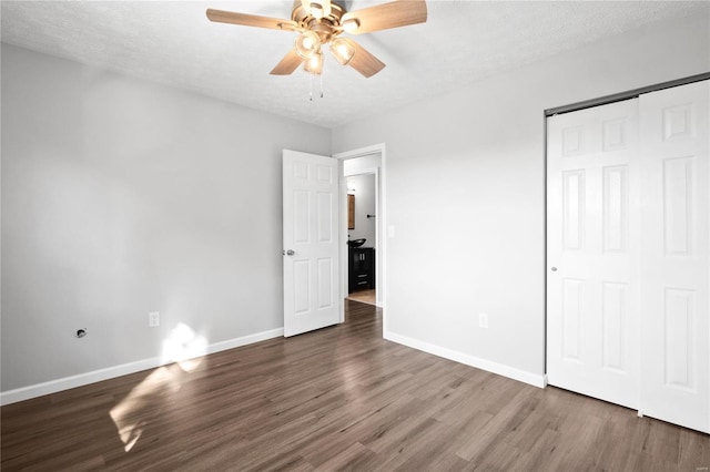 unfurnished bedroom featuring ceiling fan, dark hardwood / wood-style floors, a textured ceiling, and a closet