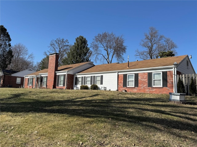 view of front of home featuring a chimney, a front lawn, and brick siding