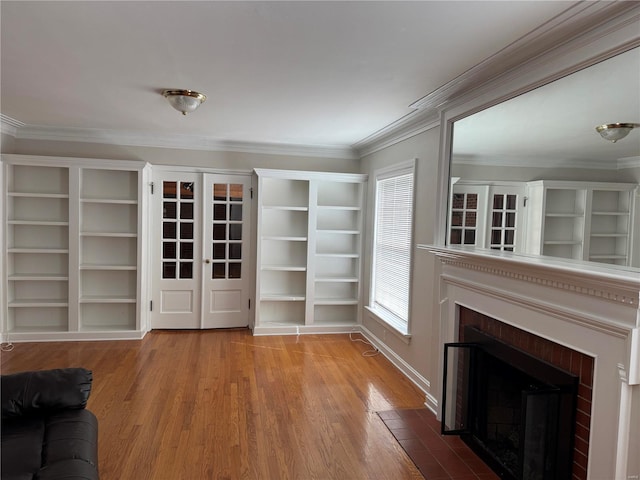 interior space featuring a fireplace with flush hearth, french doors, crown molding, and wood finished floors