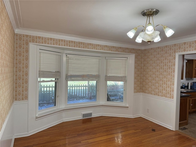 unfurnished dining area with wallpapered walls and wainscoting