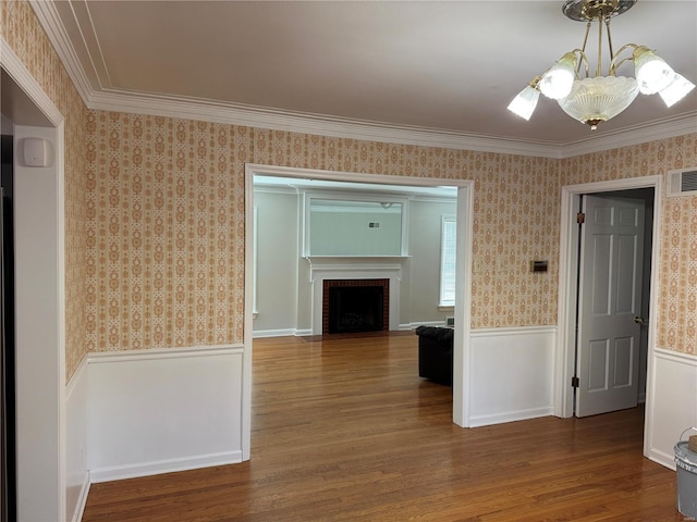 hallway featuring a chandelier, wood finished floors, wainscoting, and wallpapered walls