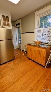 kitchen featuring dark countertops, light wood finished floors, brown cabinetry, and freestanding refrigerator