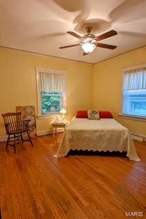 bedroom with a ceiling fan, baseboards, and wood finished floors