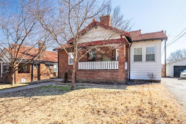 bungalow with an outbuilding, a porch, brick siding, a tile roof, and a chimney