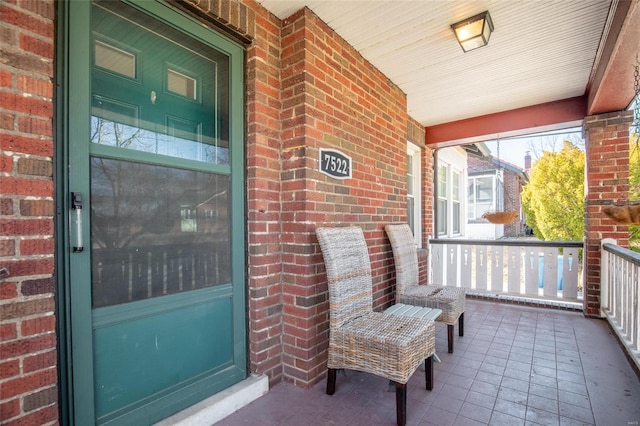 doorway to property with covered porch and brick siding