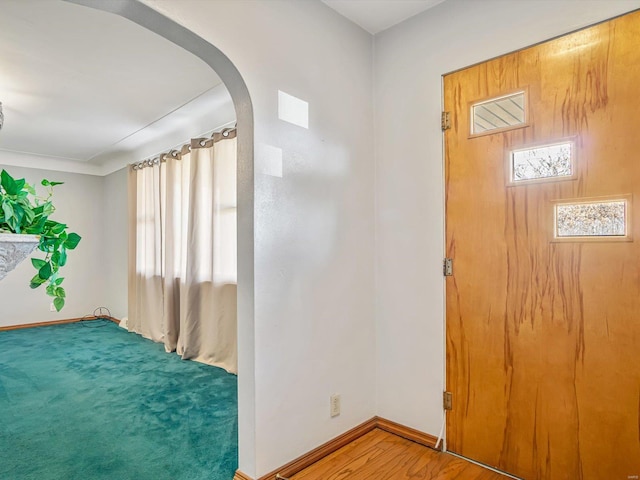 entrance foyer with baseboards, arched walkways, and wood finished floors