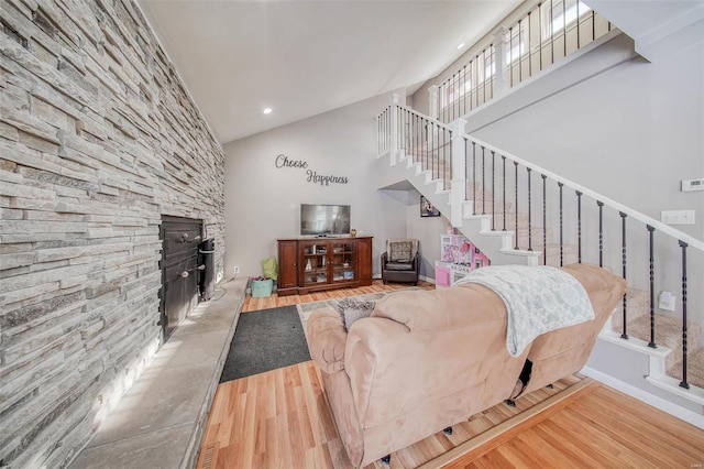 living room featuring wood finished floors, stairs, a high ceiling, a fireplace, and recessed lighting
