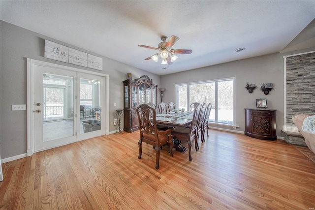 dining area featuring a ceiling fan, light wood finished floors, baseboards, and plenty of natural light