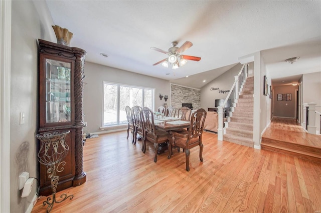 dining room featuring stairway, light wood-type flooring, a ceiling fan, and baseboards