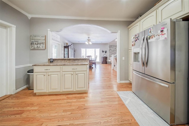 kitchen featuring stainless steel fridge with ice dispenser, arched walkways, light wood-style floors, cream cabinets, and ceiling fan